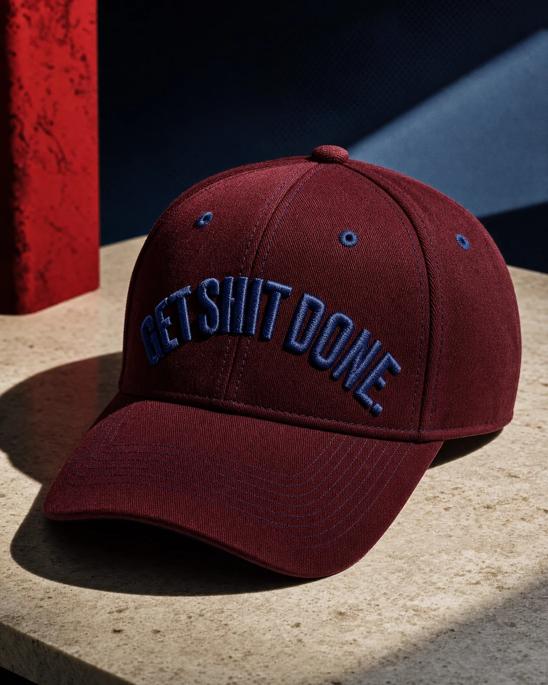 Heavy cotton-twill cap photographed as a real premium object with the exact statement “get shit done” integrated into its material.